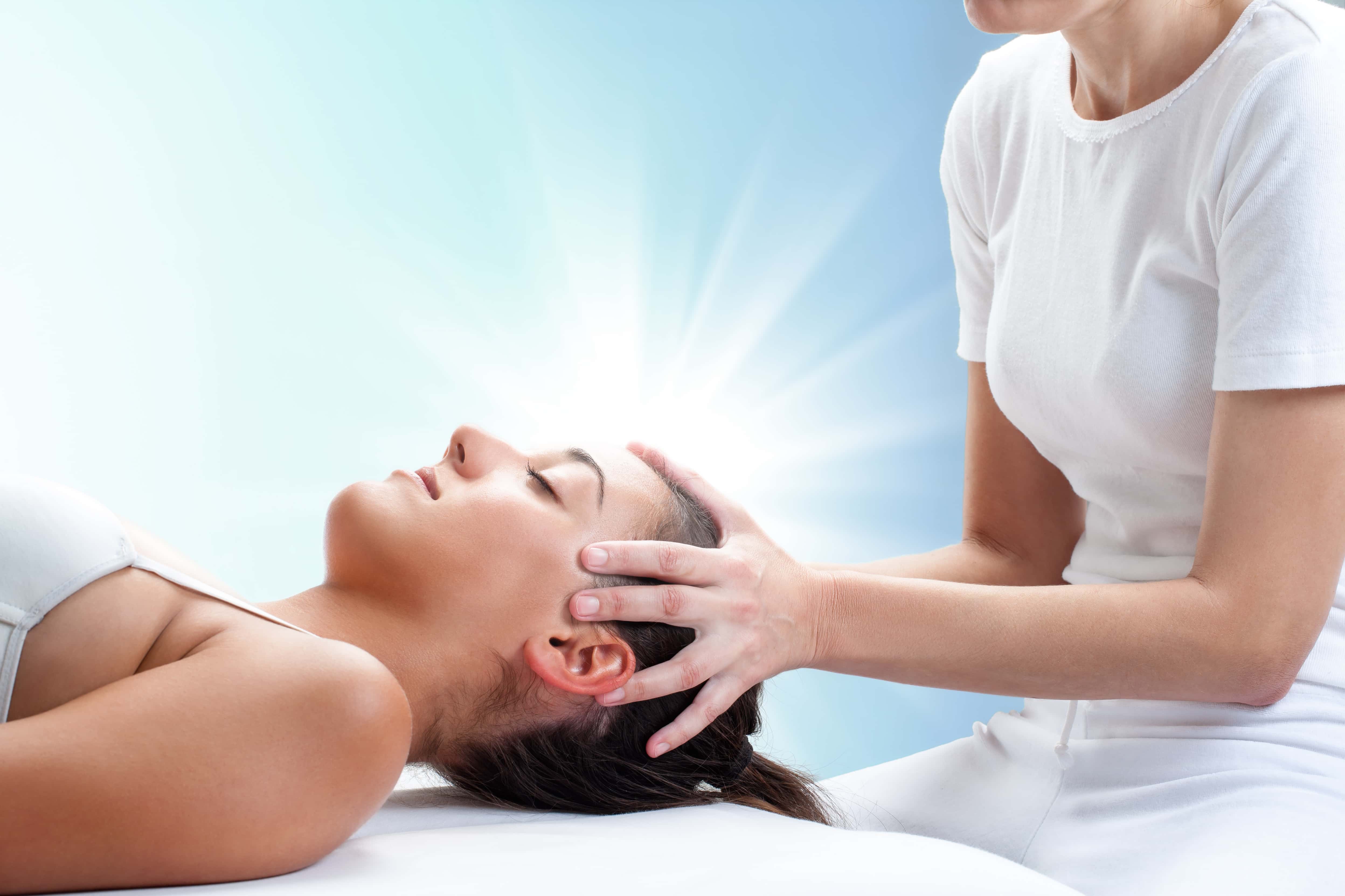 A women perfomring reiki with her hands on another women's head